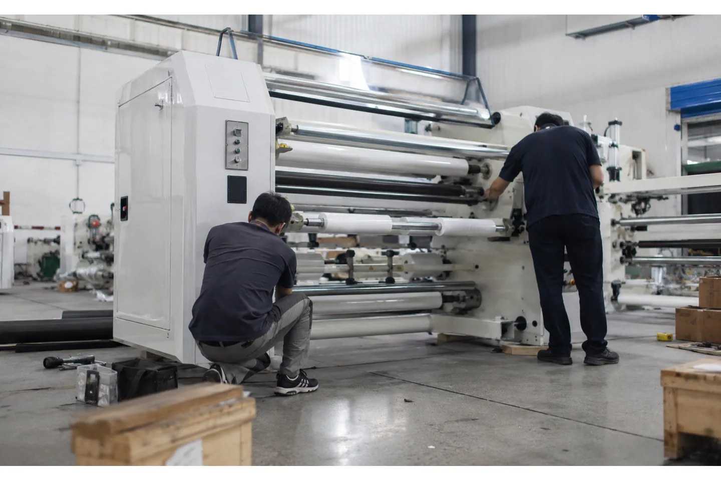Commissioning team checking a slitter rewinder web path and finished roll at an overseas converting plant